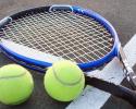 Tennis racket and two tennis balls laying on the court